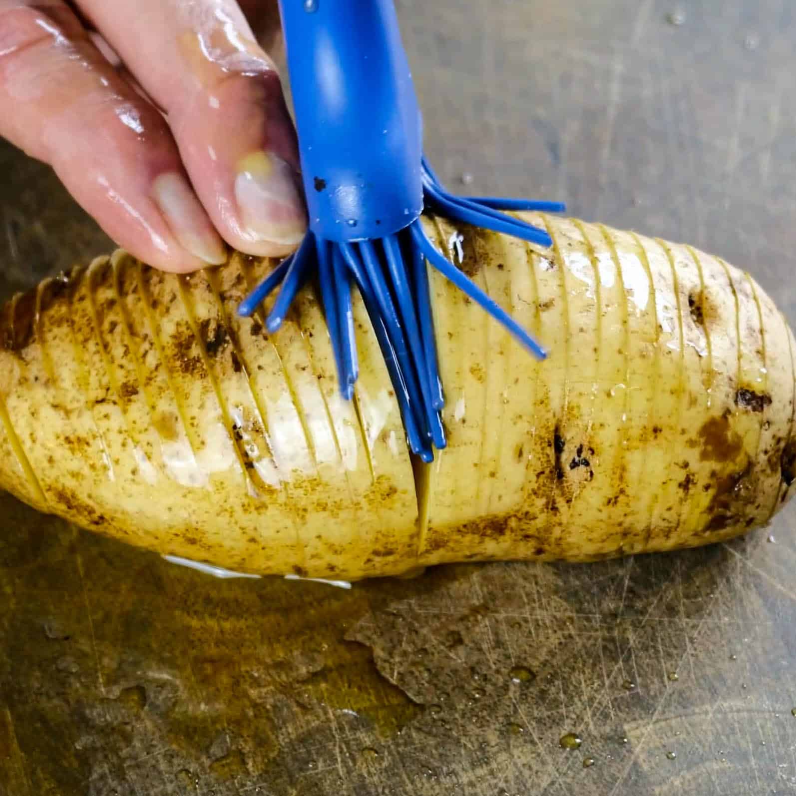 adding melted vegan butter to sliced hasselback potato_