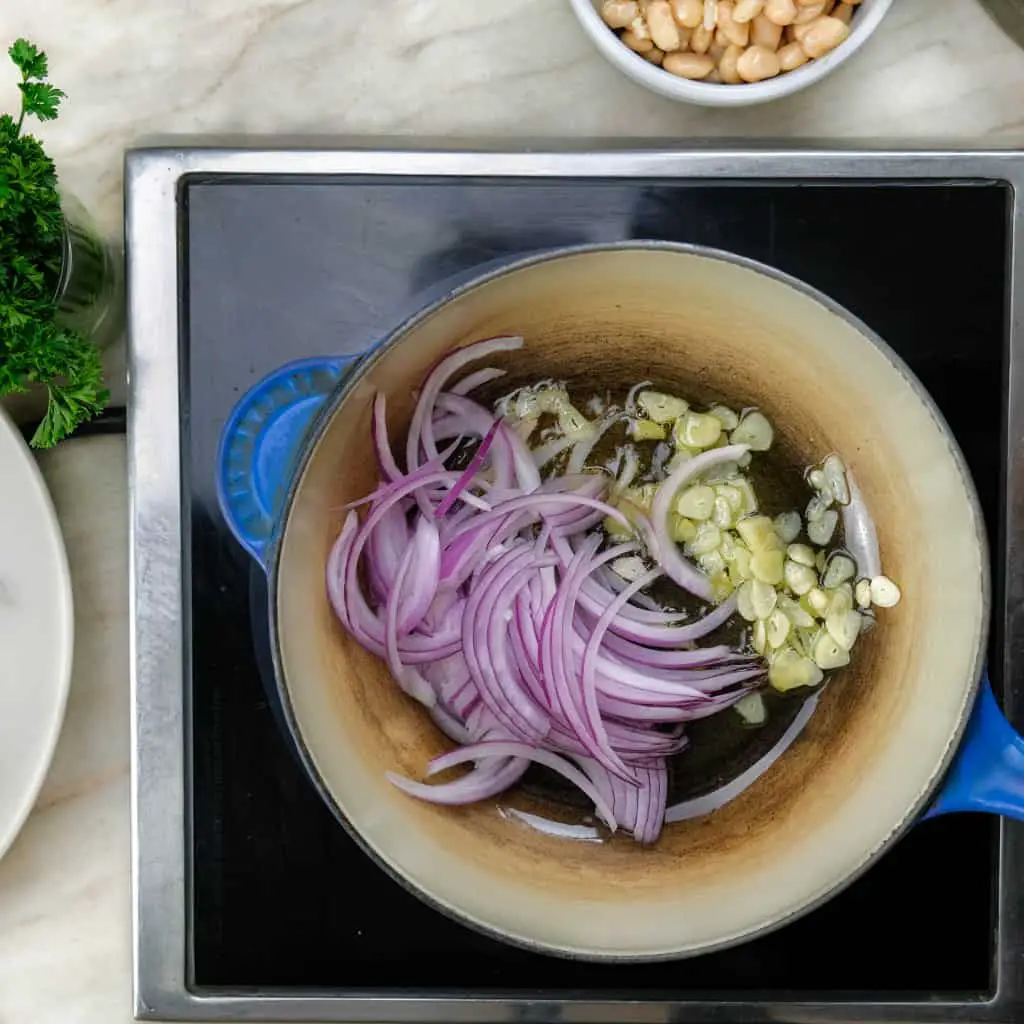 COOKING SLICED GARLIC, SLICED RED ONION WITH OLIVE OIL CREAMY BEANS